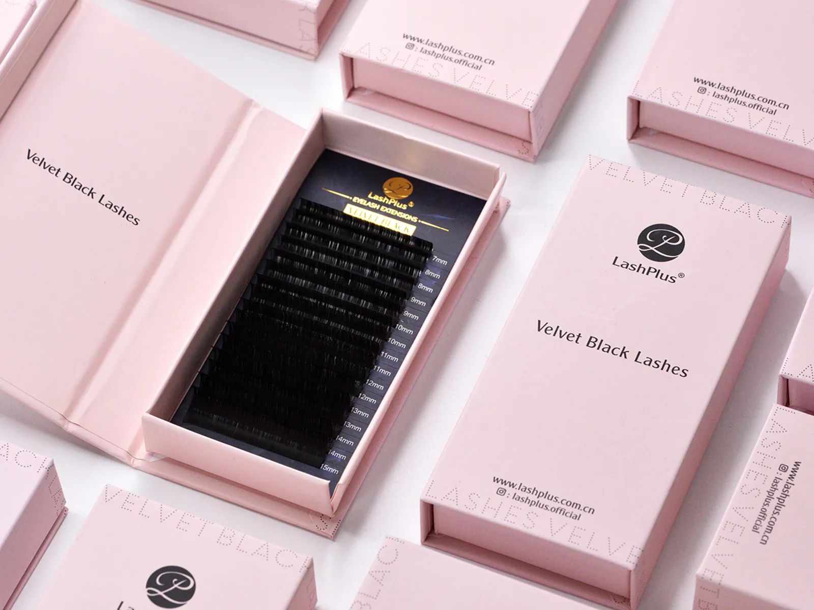 A pink magnetic rigid lash box opened to a black velvet tray, showing the snap-close lid and foil-stamped logo